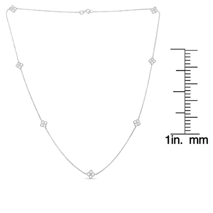 White metal necklace with round white gemstones in prong settings arranged in small floral motifs, laid flat with a ruler for size reference, top-down angle.