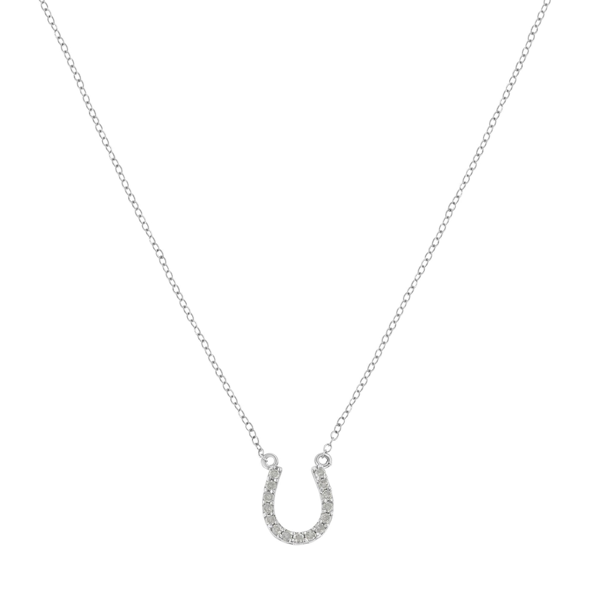 Front-facing shot of a white metal necklace with a horseshoe-shaped pendant embellished with round white gemstones in prong settings.
