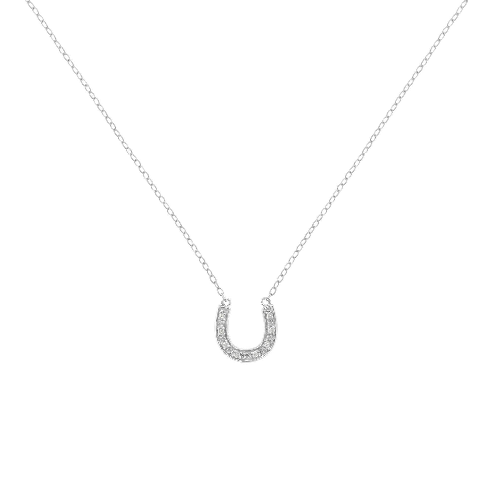 Front-facing shot of a white metal necklace with a horseshoe-shaped pendant set with small round white gemstones in a pave setting.
