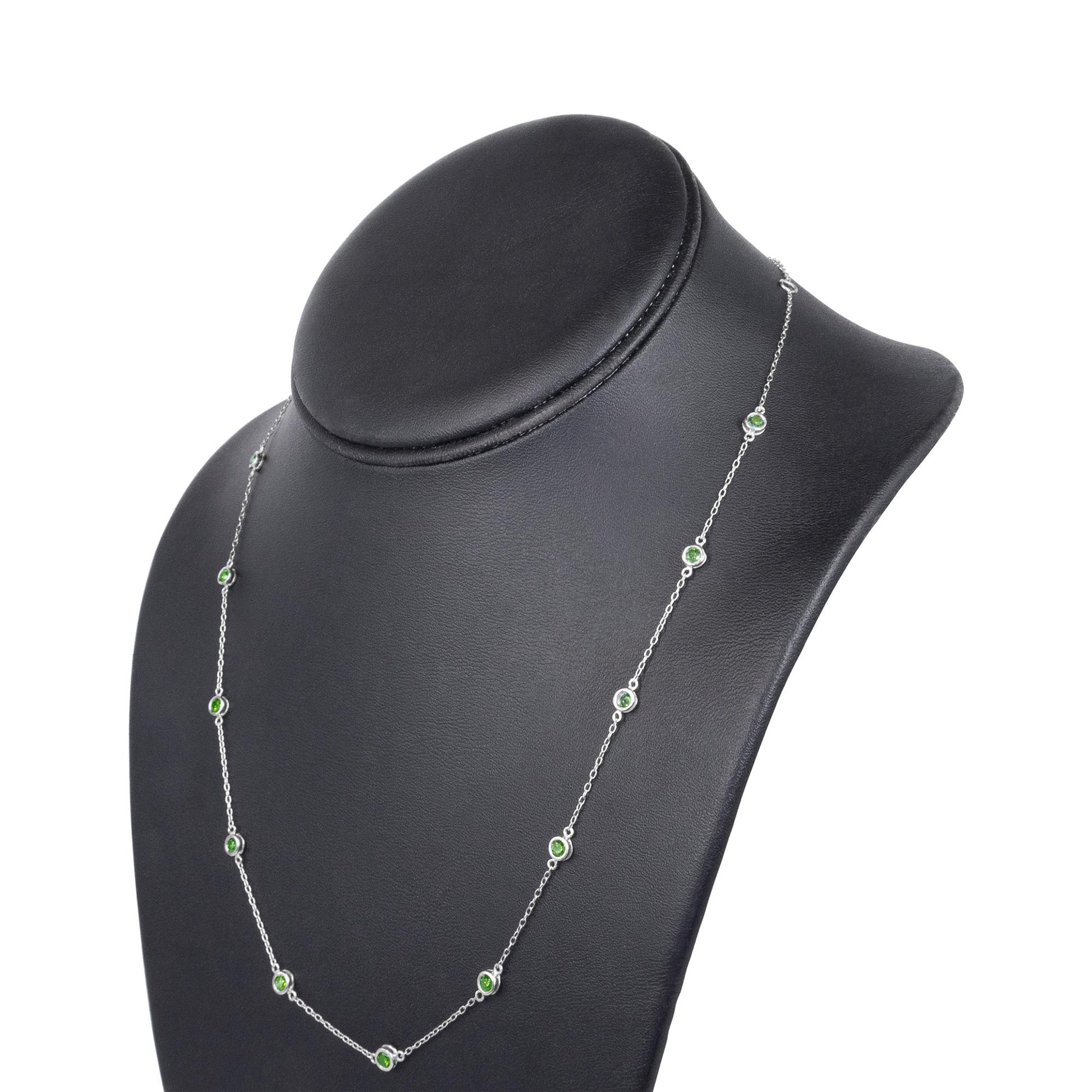 White metal necklace with round green gemstones in bezel settings, displayed on a black jewelry bust at a slight angle.