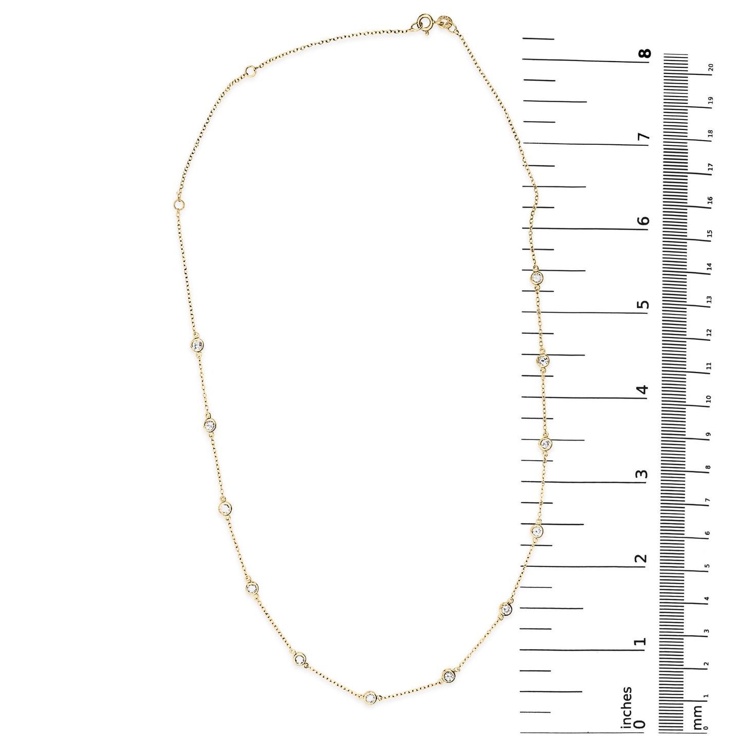 Oval-shaped yellow necklace with round white gemstones in bezel settings, displayed flat next to a ruler for size reference, shot from above.