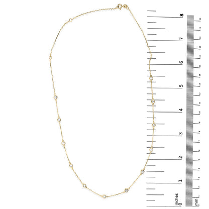 Oval-shaped yellow necklace with round white gemstones in bezel settings, displayed flat next to a ruler for size reference, shot from above.