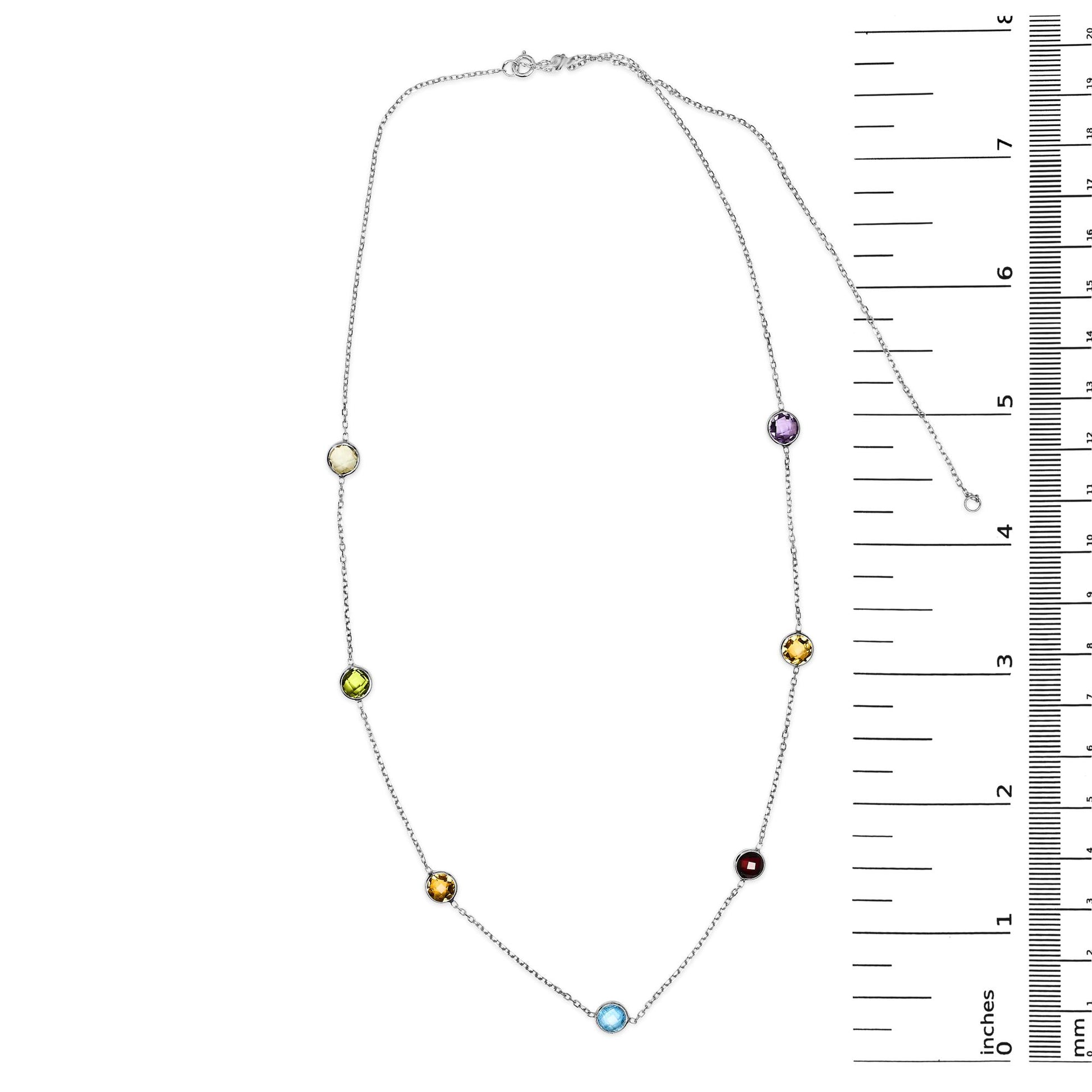 White metal necklace with round bezel-set gemstones in multiple colors including blue, purple, red, white, smoky, and yellow, displayed flat next to a ruler for size reference, top-down angle.