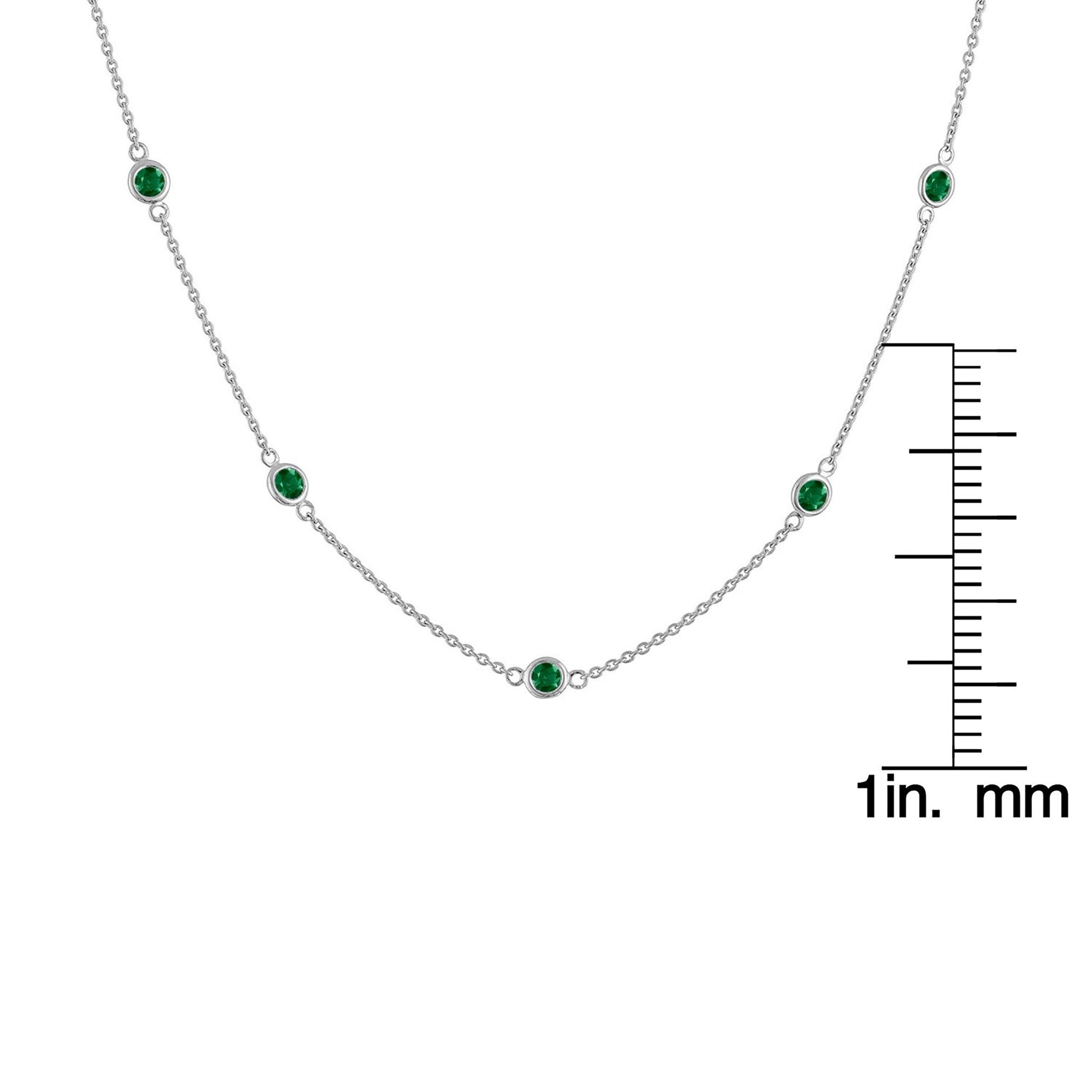 Front view of a white metal necklace with round bezel-set green gemstones, displayed with a ruler for size reference.