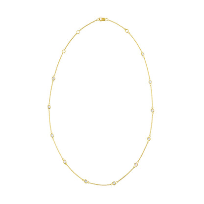 Front-facing shot of a yellow metal necklace with small round white gemstones in bezel settings evenly spaced along the chain.