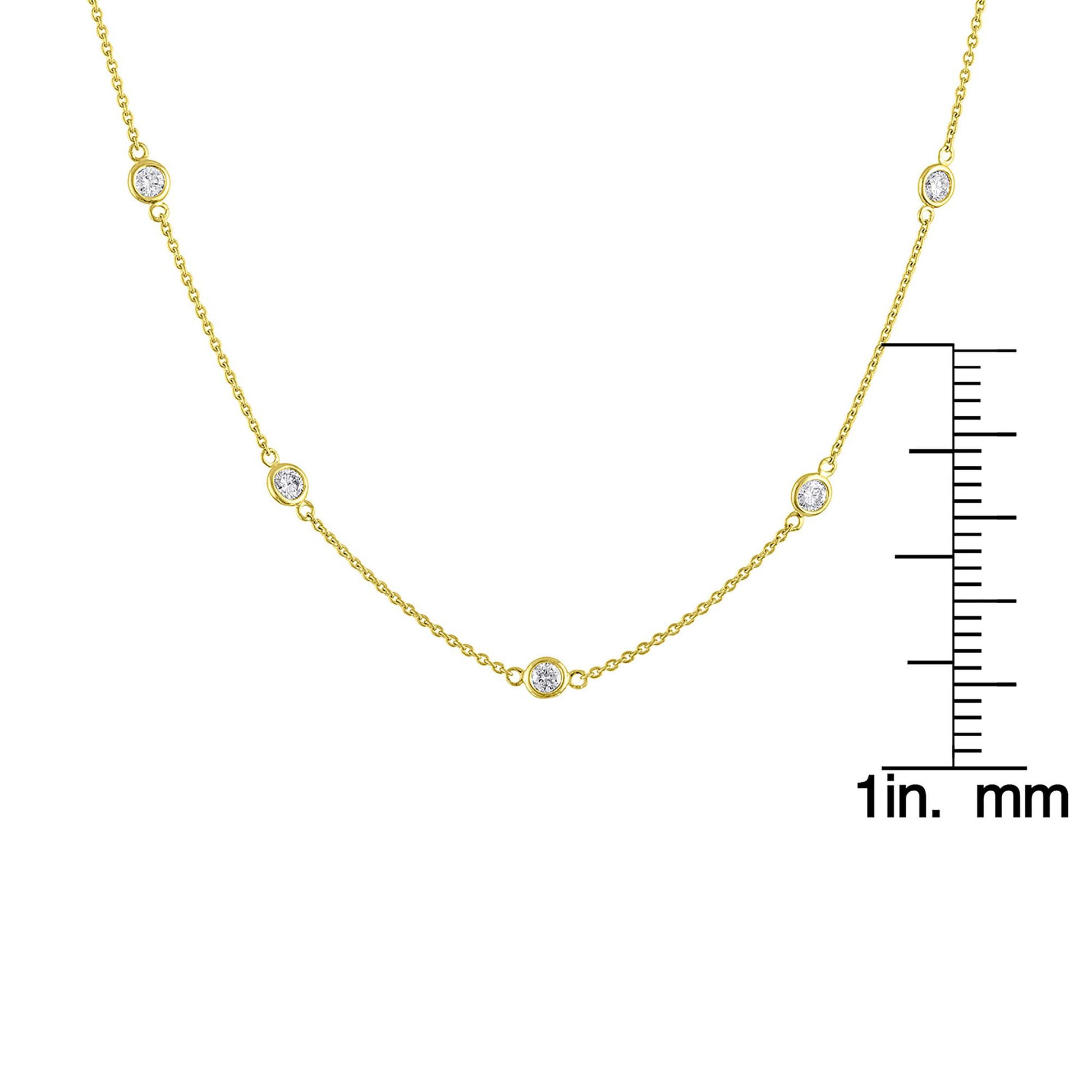 Close-up front view of a yellow metal necklace with round white gemstones in bezel settings spaced along the chain, shown on a scale.