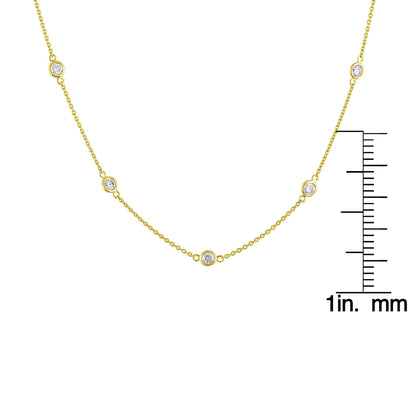 Close-up front view of a yellow metal necklace with round white gemstones in bezel settings spaced along the chain, shown on a scale.