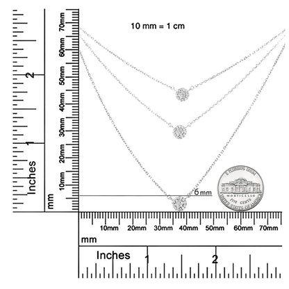 Top-down shot of three white metal necklaces with round-shaped white gemstones in prong settings, displayed on a ruler and a coin for size reference.