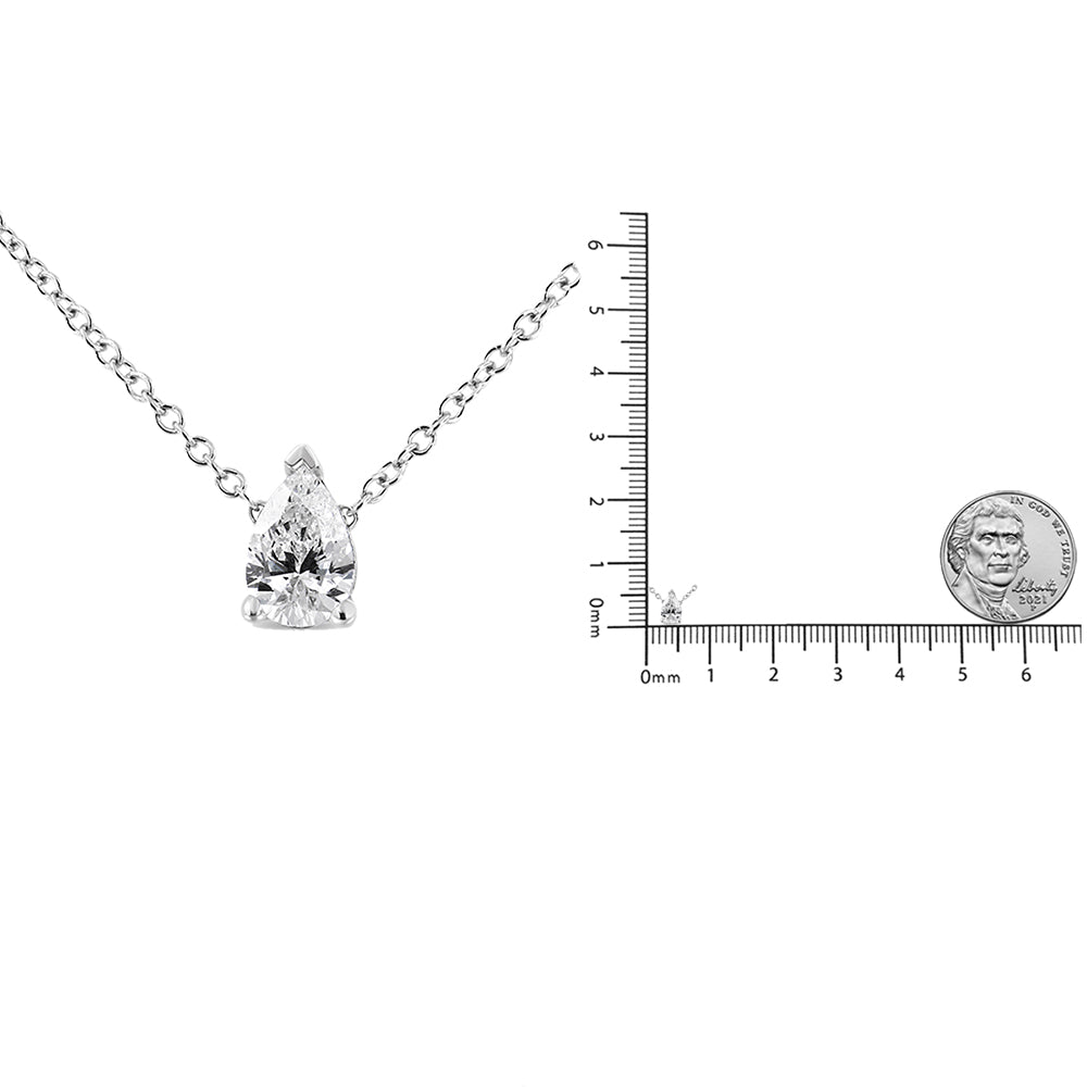 Front view of a white metal necklace with a single pear-shaped white gemstone in a prong setting, displayed next to a ruler and coin for size reference.