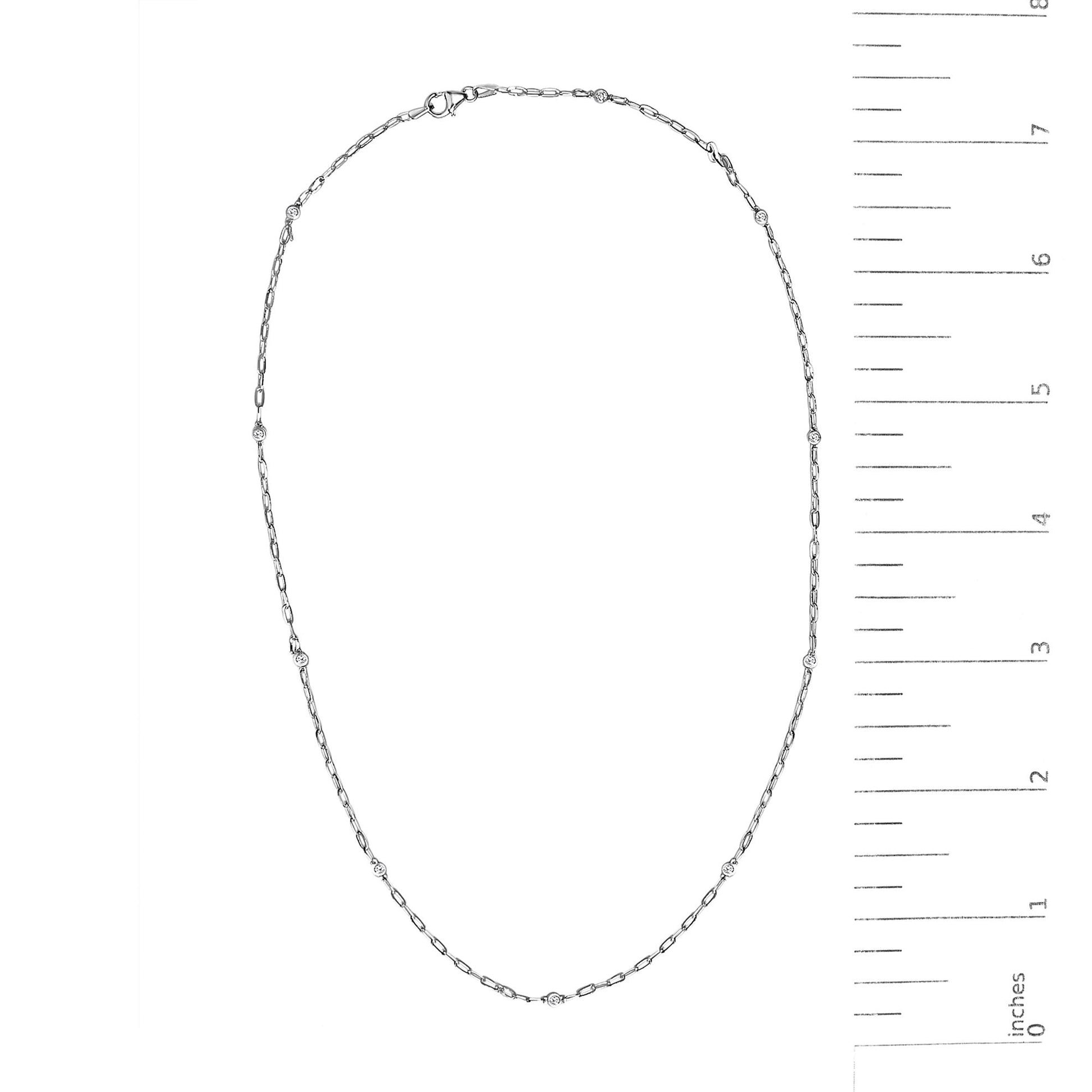 White necklace with round bezel-set white gemstones spaced along a delicate chain, shown on a scale, top-down view.