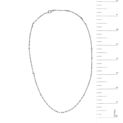 White necklace with round bezel-set white gemstones spaced along a delicate chain, shown on a scale, top-down view.