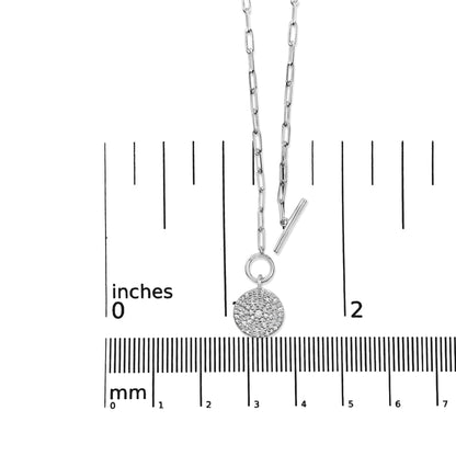 White metal necklace with round white gemstones in prong settings on a circular pendant, shown on a ruler for size reference, front view.