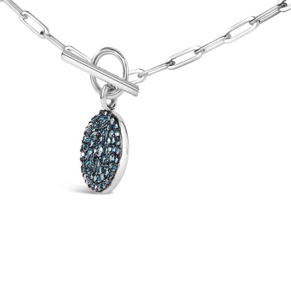 Close-up side angle of a white metal necklace with a toggle clasp featuring a round pendant encrusted with multiple small blue gemstones.