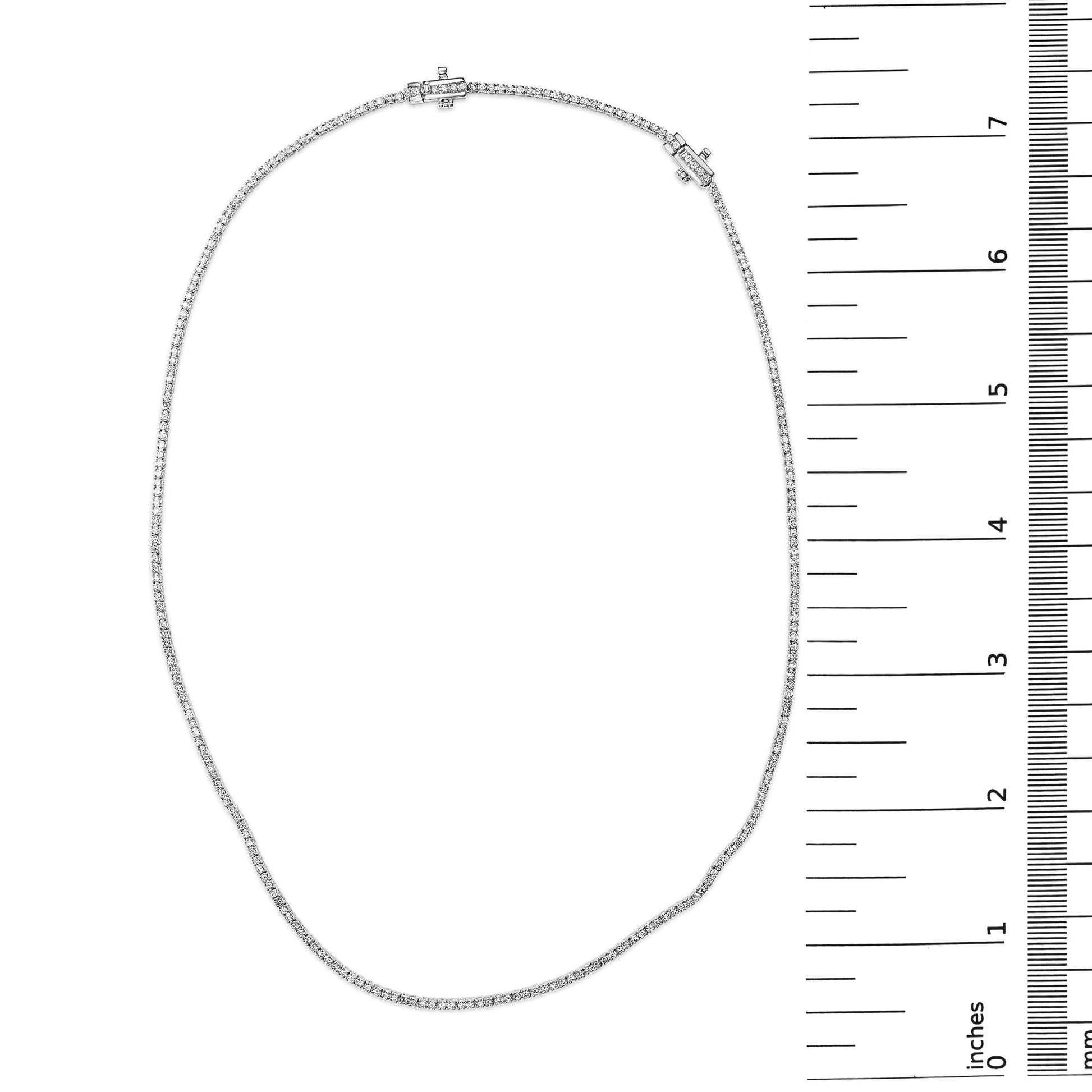 Top-down view of a white metal necklace with prong-set round white gemstones, shown alongside a ruler for size reference.