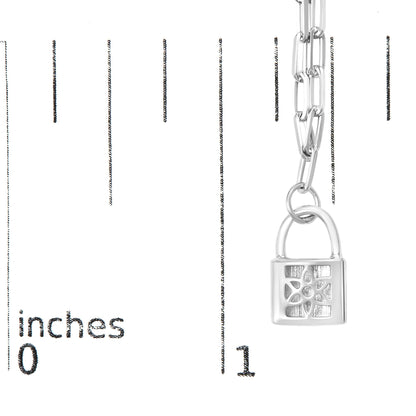Close-up front angle of a white metal necklace with a padlock pendant featuring a floral design accented with round white gemstones, shown on a ruler for size reference.