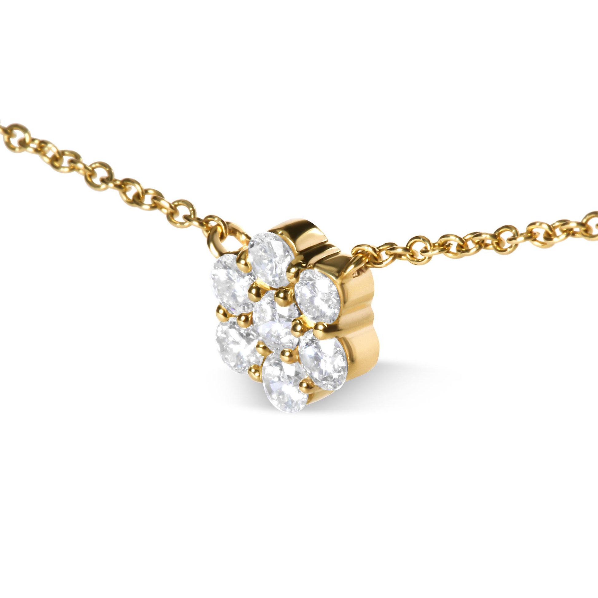 Close-up angle of a yellow metal necklace with a pendant featuring round white gemstones in a prong setting arranged in a cluster.