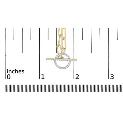 Close-up front view of a yellow metal necklace pendant with a circular design and a horizontal bar across it, both adorned with white round gemstones, shown on a ruler for size reference.