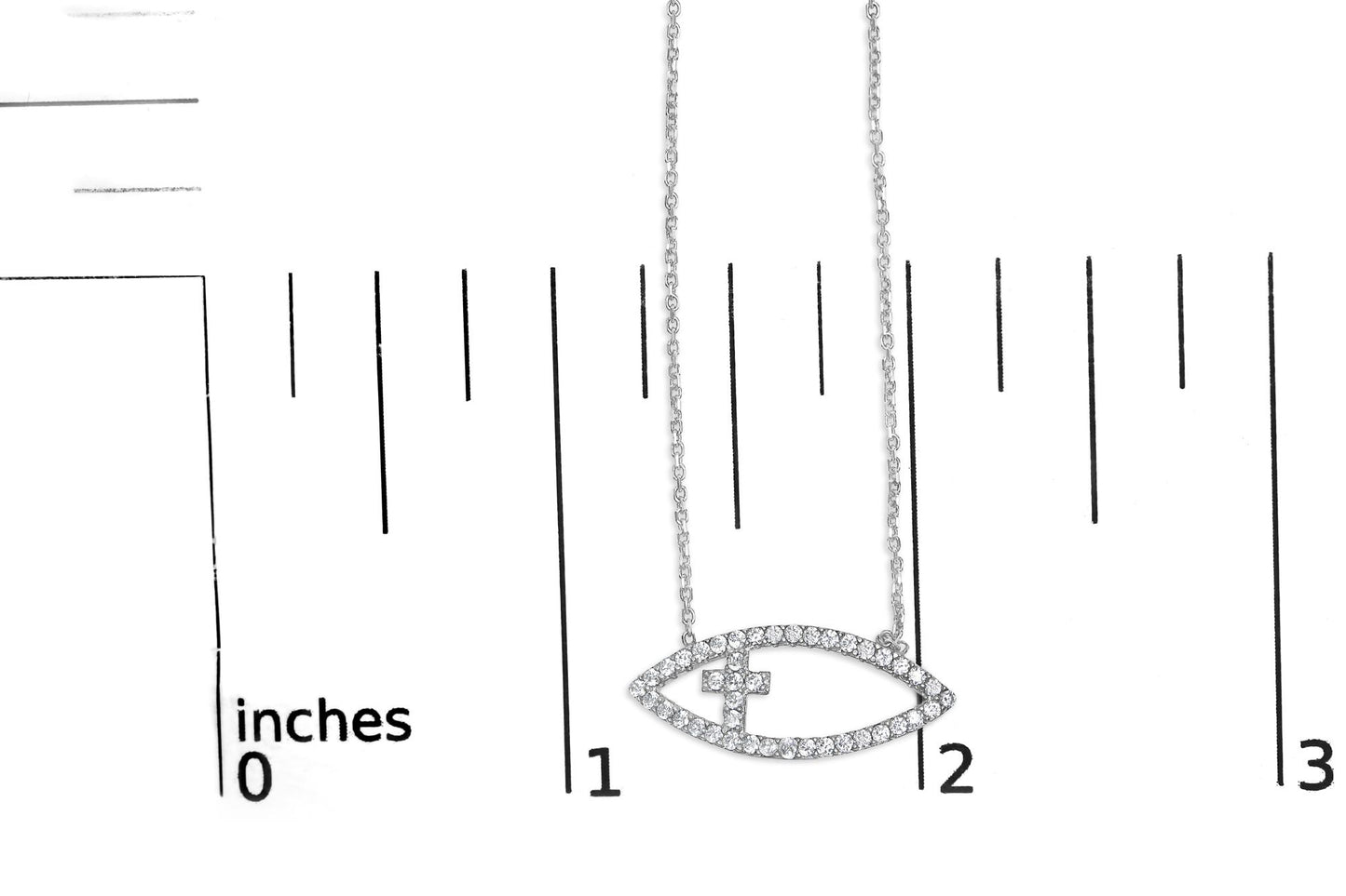 White necklace with an eye-shaped pendant encrusted with round white gemstones in prong setting, shown on a ruler for size reference, front-facing angle.
