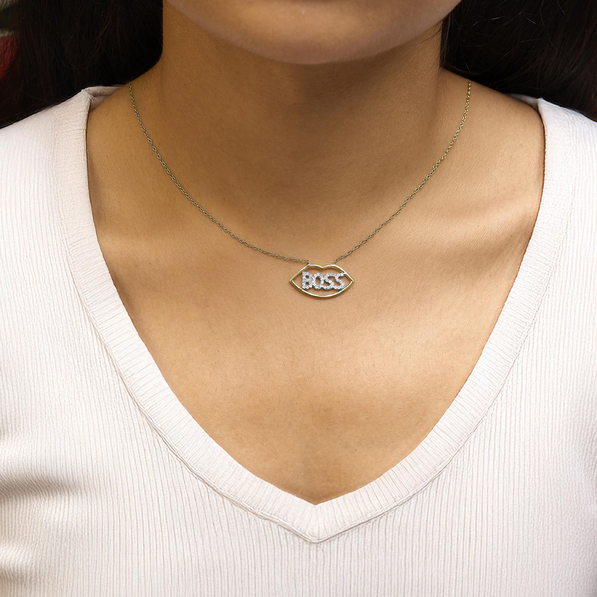 Necklace shown worn on a model, featuring a yellow and white metal chain with a pendant shaped like an eye containing the word 'BOSS' in white gemstones, photographed from the front.