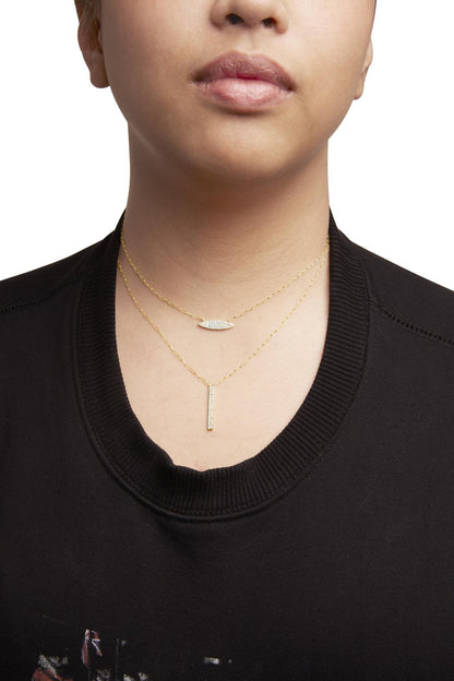 Front view of a model wearing two layered yellow necklaces featuring white round gemstones in prong settings, one with a horizontal marquise-shaped pendant and the other with a vertical bar pendant.