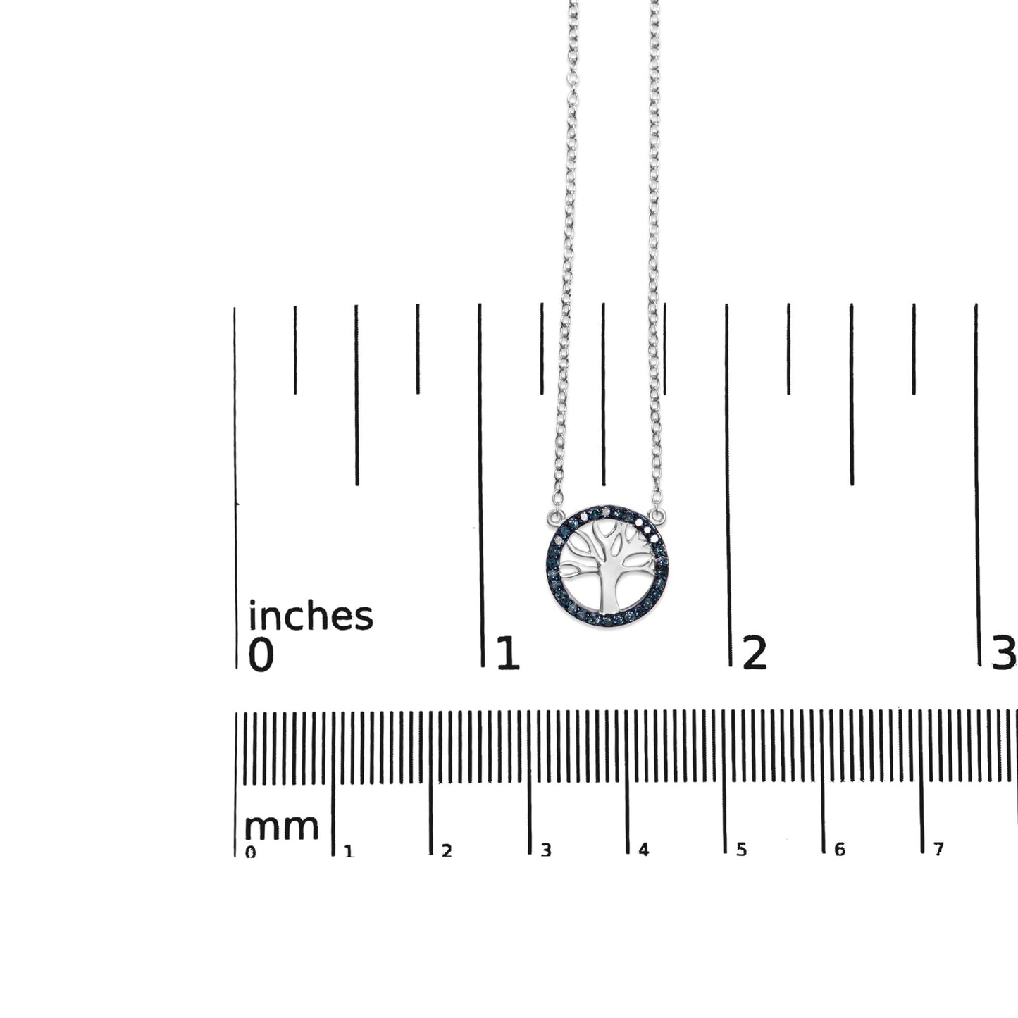White metal necklace with round prong-set blue gemstones forming a circle around a tree-shaped pendant, shown from a top-down angle on a ruler for size reference.