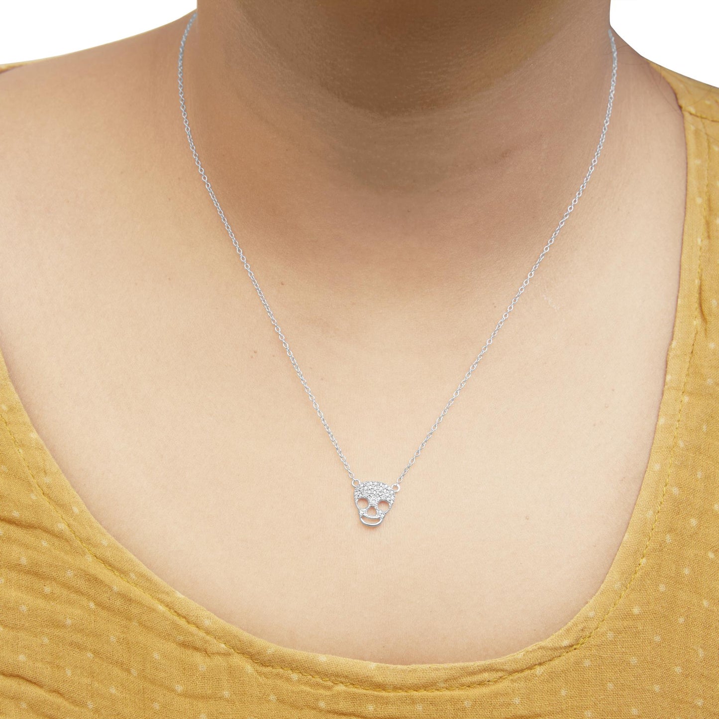 White metal necklace with a skull-shaped pendant adorned with round white gemstones, worn on a model, front-facing angle.