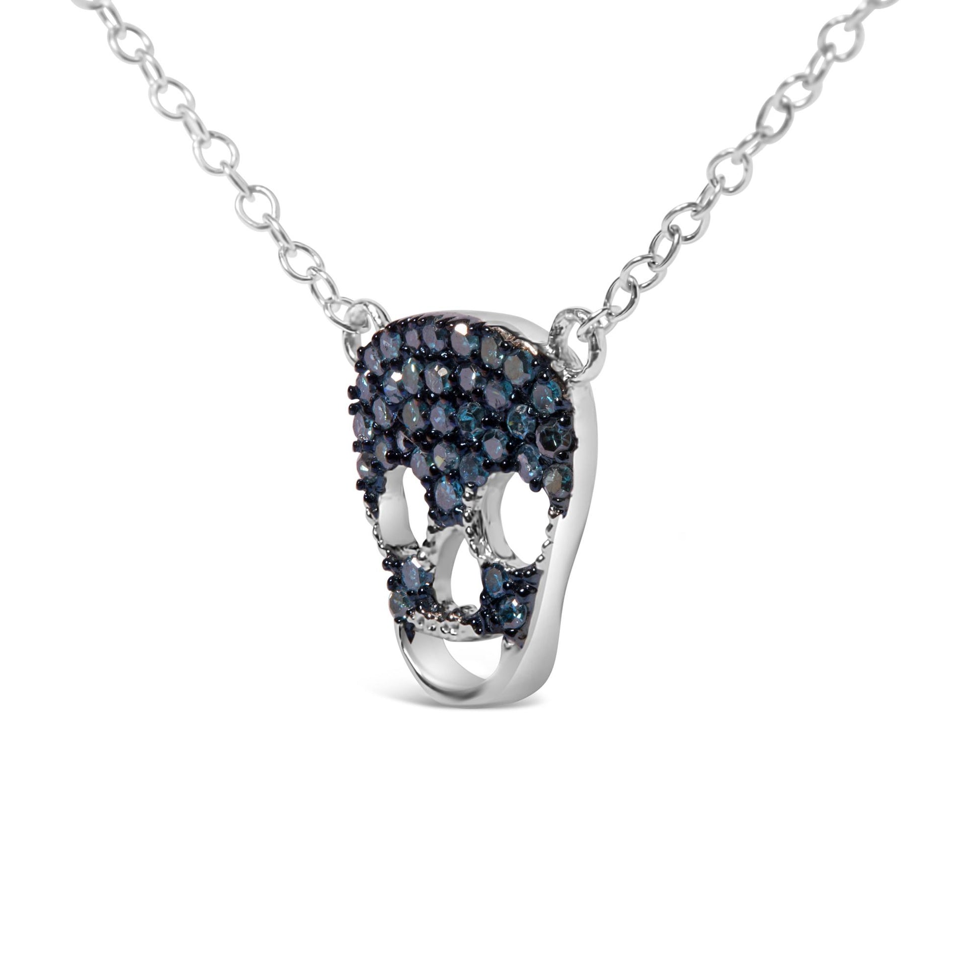 White metal skull-shaped necklace pendant with multiple prong-set round blue gemstones, shown in a front close-up angle.