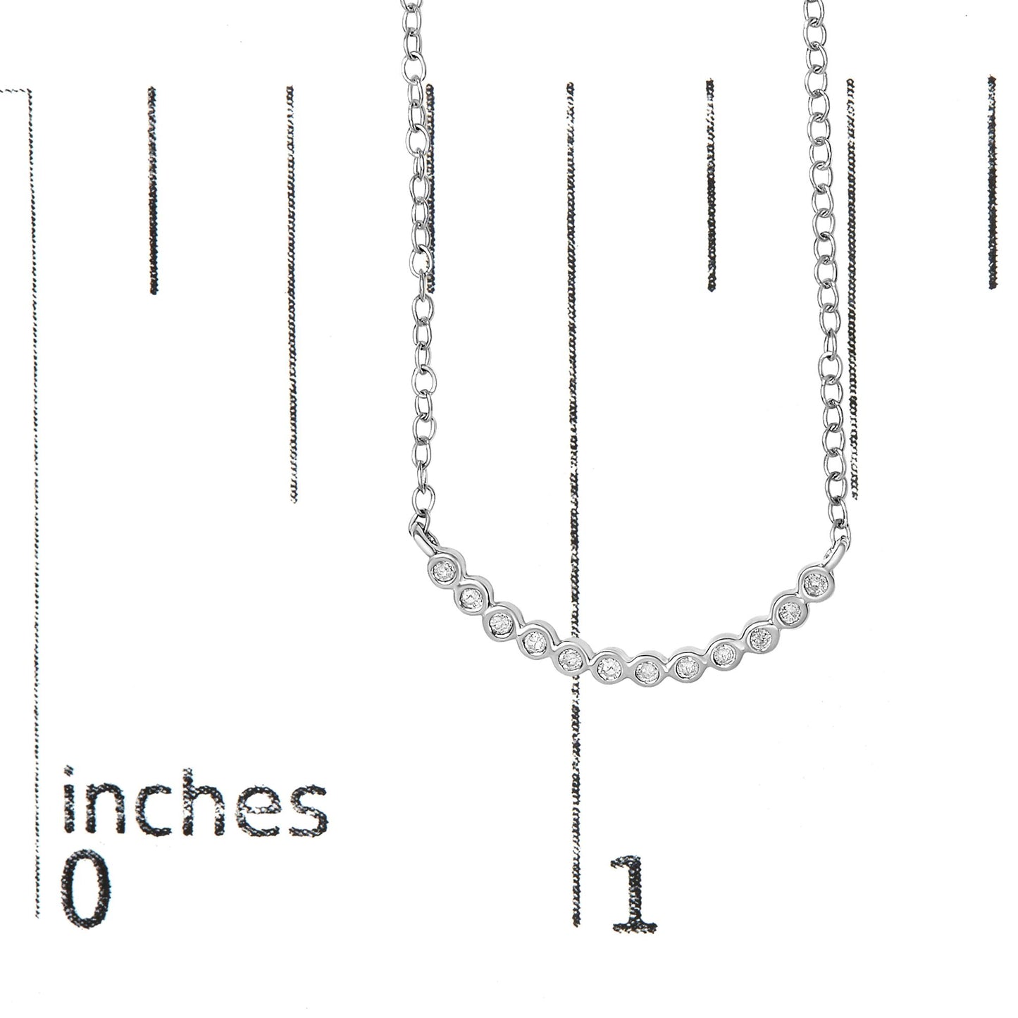 White metal necklace with a curved bar featuring a row of round white gemstones in prong settings, shown on a scale with inch markings, front view.