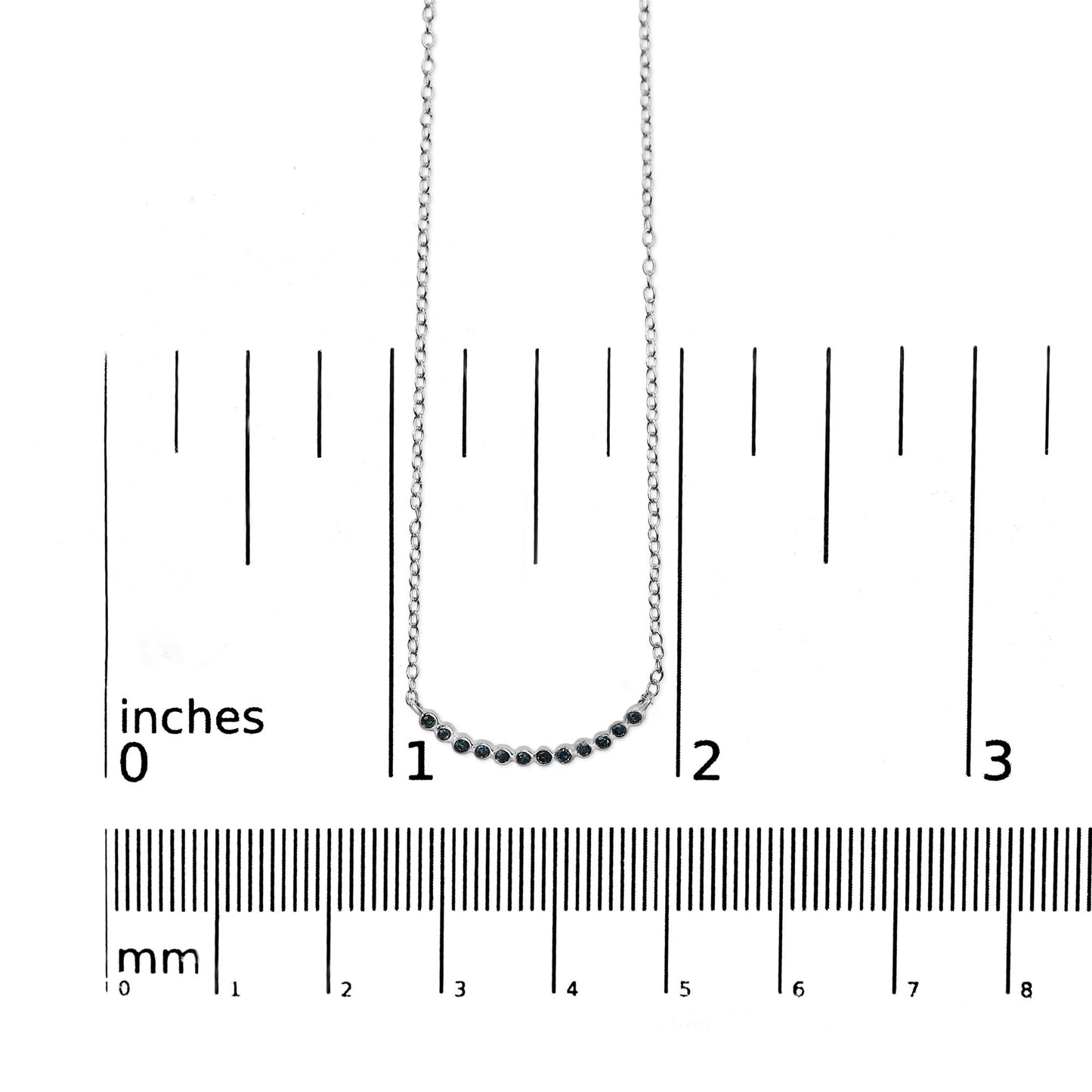 White necklace with a curved bar featuring round blue gemstones in prong settings, shown on a scale from a front angle.
