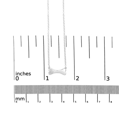 White metal necklace with a bone-shaped pendant featuring three round white gemstones in prong settings, displayed on a ruler for size reference, front angle.