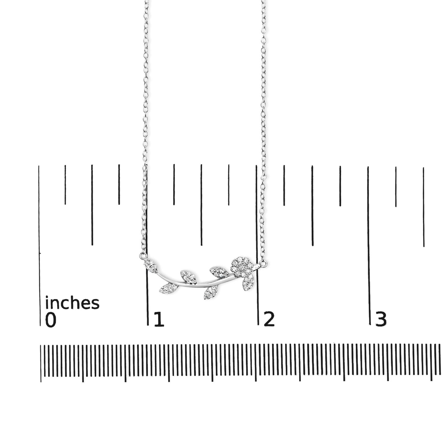 White metal necklace with a floral and leaf design adorned with round white gemstones in prong settings, shown hanging on a ruler for size reference, front view.
