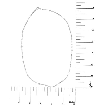 White metal necklace with small round white gemstones in bezel settings evenly spaced along a delicate chain, shown flat on a scale from above.
