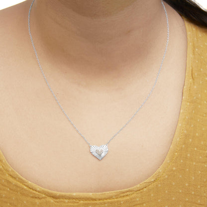 Close-up front view of a white metal necklace on a model, featuring a heart-shaped pendant with a textured design and small white gemstones clustered in the center.