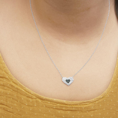 Front view of a white necklace with a heart-shaped pendant featuring a textured design and a smaller heart adorned with blue round gemstones, worn on a model.