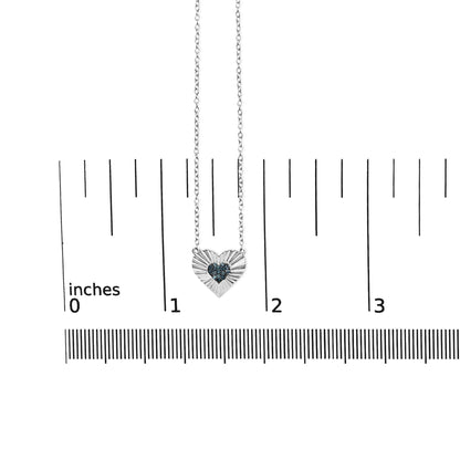 White metal heart-shaped necklace with a cluster of round blue gemstones in the center, shown from the front on a ruler for size reference.