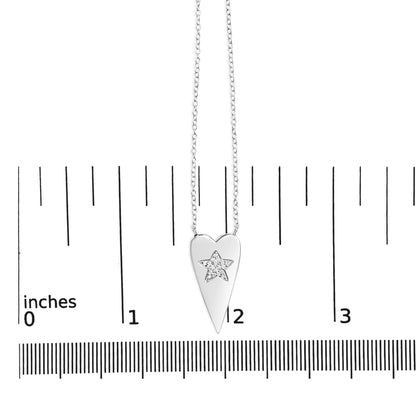 Close-up front view of a white metal necklace with a pendant shaped like a pointed elongated heart. The pendant features a star design inset with small round white gemstones in a prong setting. The necklace is shown on a scale.