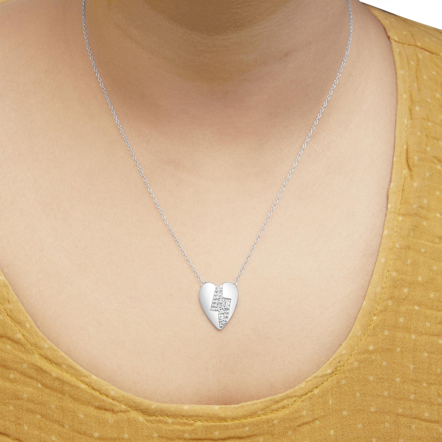 White metal heart-shaped necklace with a lightning bolt design featuring round white gemstones in a prong setting, worn on a model, front view.