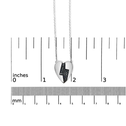 White metal heart-shaped necklace pendant with a zigzag design filled with blue round prong-set gemstones, shown from the front on a ruler for size reference.