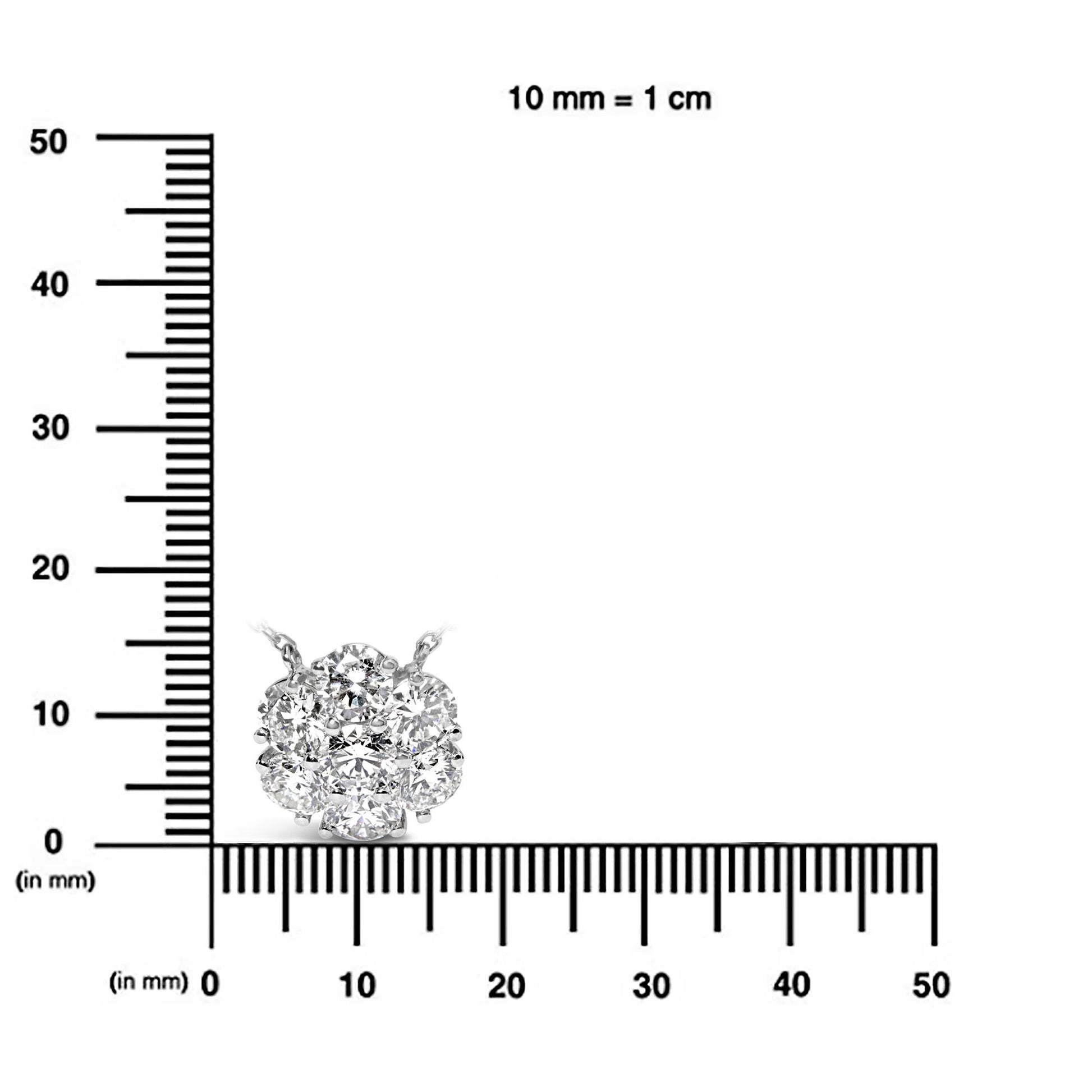 Close-up front view of a white necklace pendant with round white gemstones in prong settings, placed on a ruler for size reference.