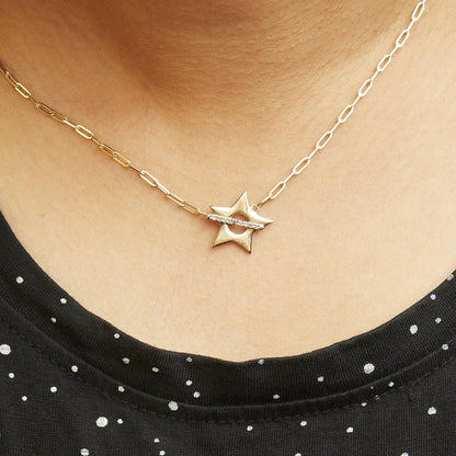 Yellow metal necklace with a star-shaped pendant featuring a horizontal row of white round gemstones in prong settings, shown worn on a model from a close-up front angle.