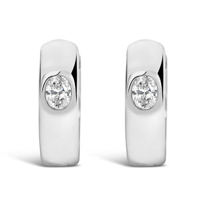 Close-up front view of white metal earrings featuring oval-shaped white gemstones in bezel settings.