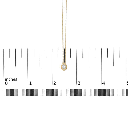 Yellow necklace with an oval white gemstone in bezel setting shown on a scale from a front angle.