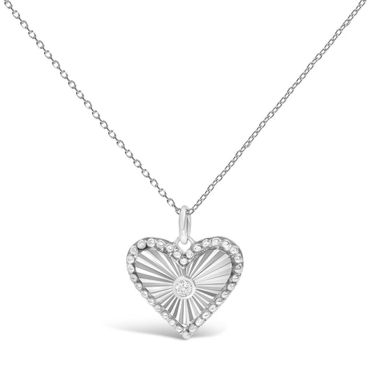 Close-up front view of a white metal necklace with a heart-shaped pendant featuring radiating lines, a beaded border, and a single round white gemstone in a bezel setting at the center.