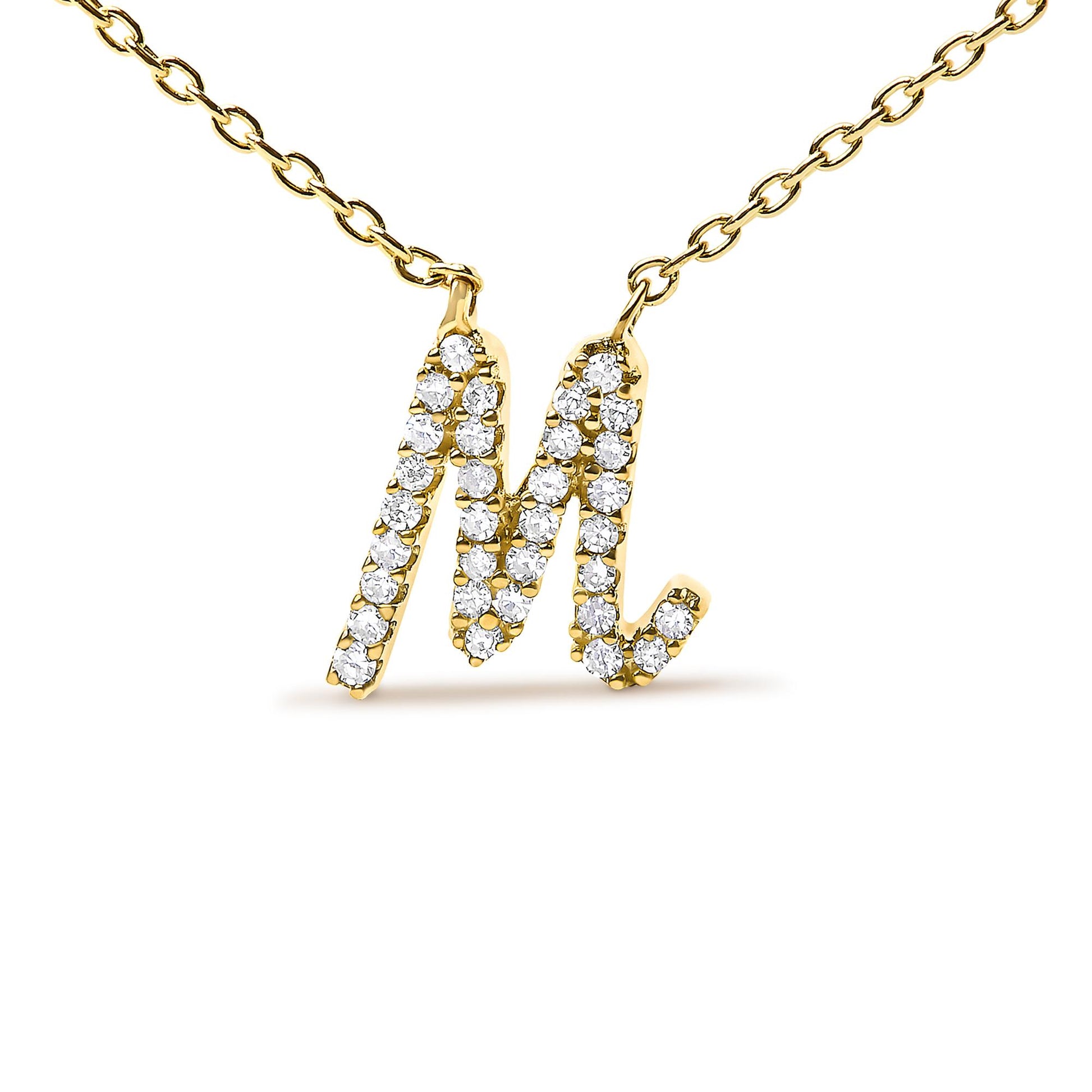 Close-up front angle of a yellow metal necklace with a pendant shaped like the letter M, encrusted with round white gemstones in a micro-pave setting.