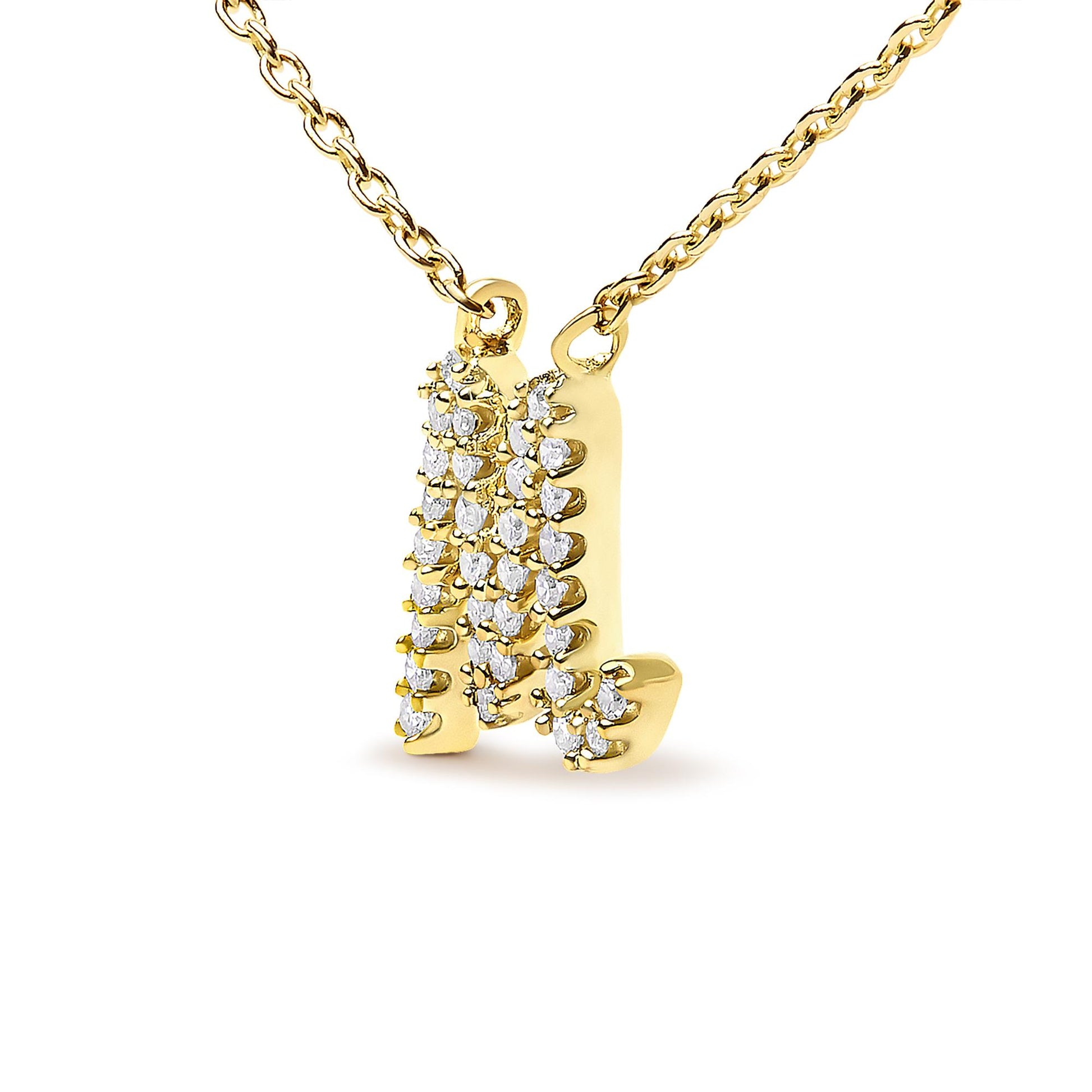 Close-up front angle of a yellow metal necklace pendant shaped like the letter M, adorned with multiple white gemstones in a micro-pave setting.