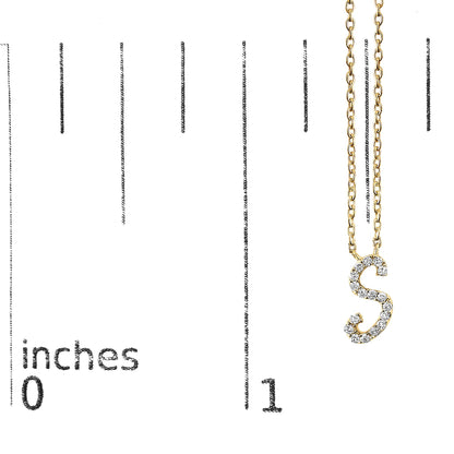 Close-up front view of a yellow metal necklace with a pendant in the shape of the letter 'S' adorned with small white gemstones, shown hanging on a scale marked in inches.