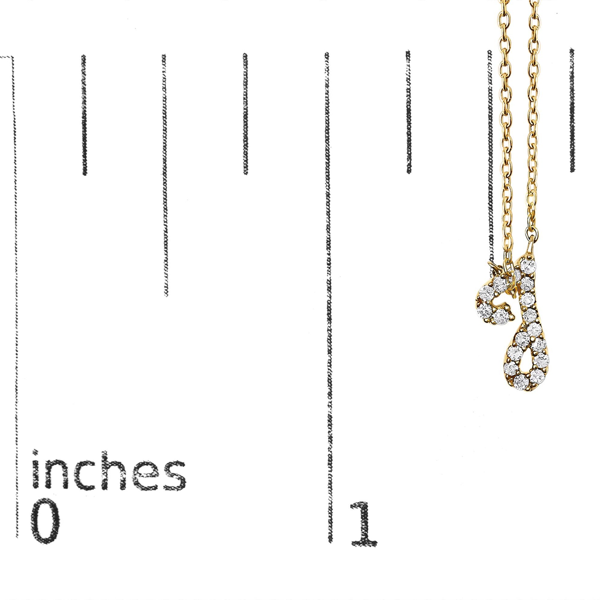 Close-up of a yellow necklace pendant with two script letter charms adorned with round white gemstones in a micro-pave setting, shown on a vertical scale.