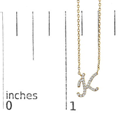 Close-up front view of a yellow metal necklace with a pendant shaped as the letter 'K,' adorned with white round gemstones in a micro-pave setting, shown on a measurement scale.