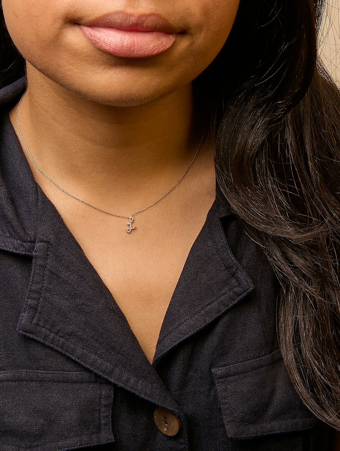 Close-up front view of a model wearing a delicate yellow necklace with a pendant adorned with small round white gemstones in a micro-pave setting.
