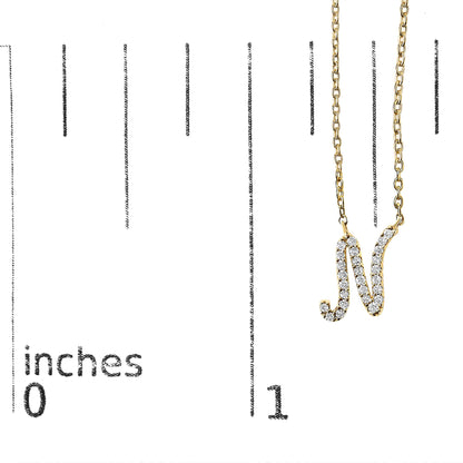 Yellow metal necklace pendant shaped like the letter N, decorated with multiple white round gemstones in a micro-pave setting, shown on a scale from a front angle.